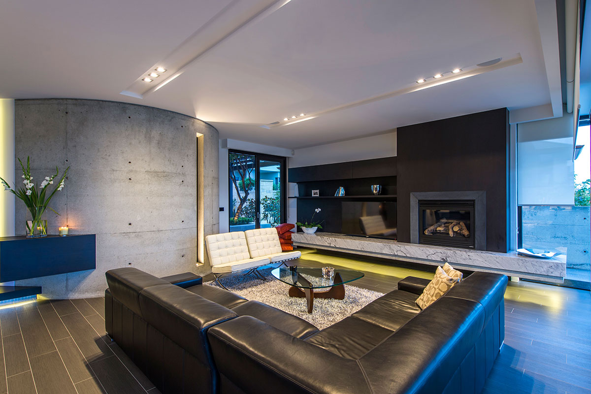 The magnificence of this lounge room is evident in its curved concrete wall, enormous spacious design all centered around its marble plinth and open fireplace